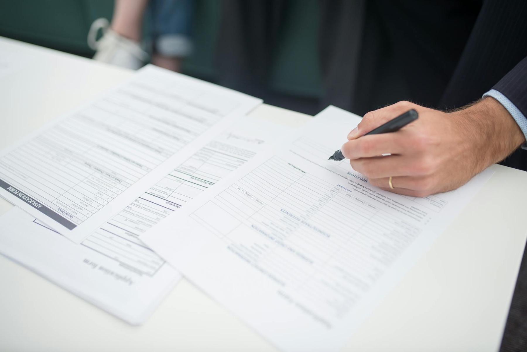 A man diligently writes on a sheet of paper using a pen