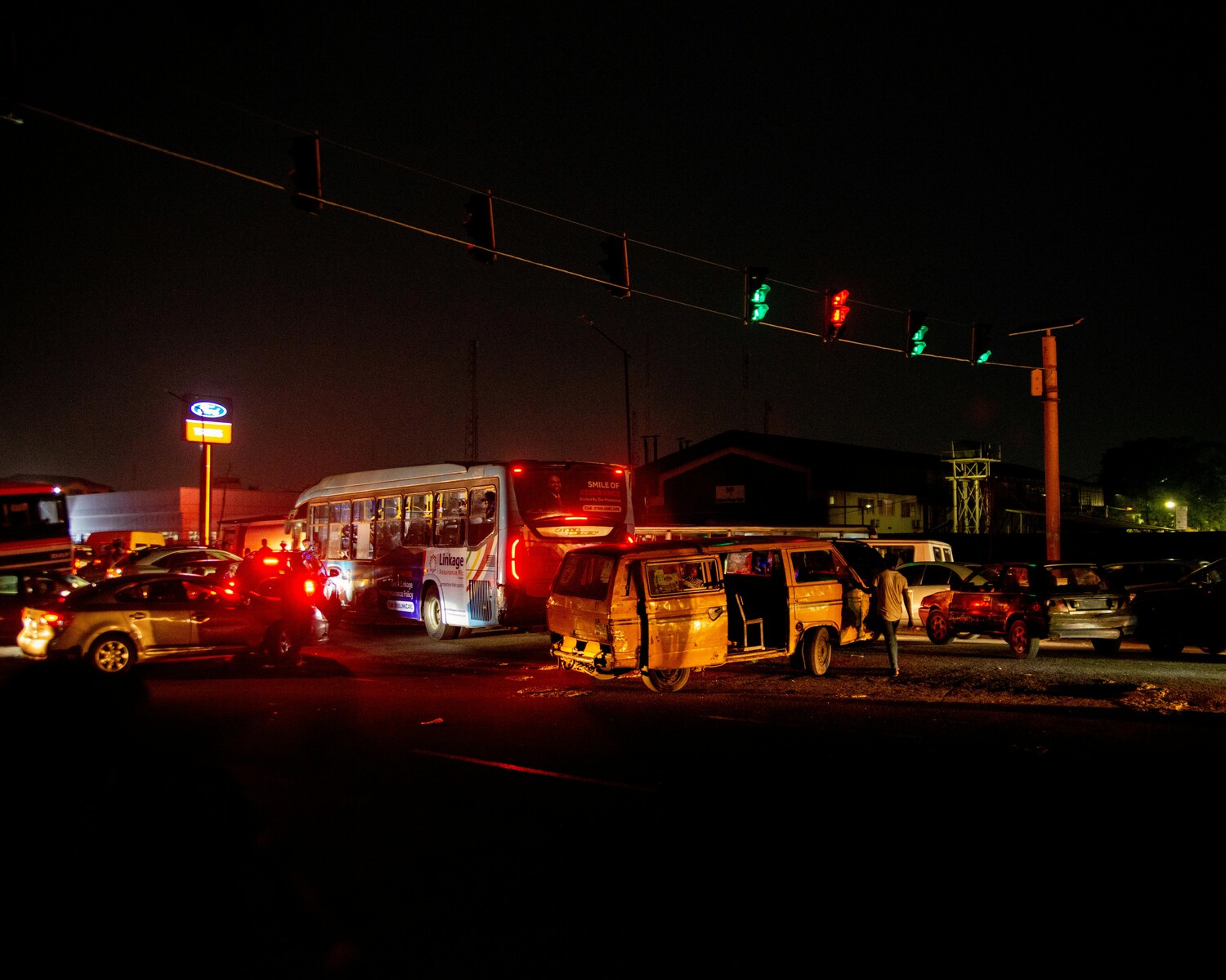 Traffic stopped at a nighttime intersection with illuminated traffic lights.